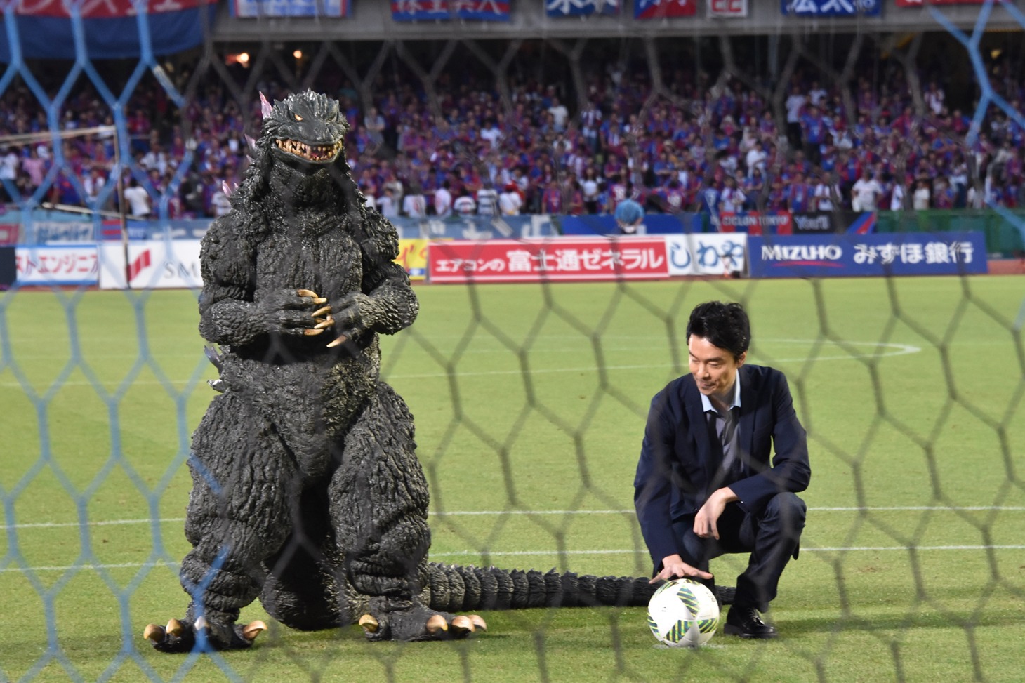 ボールをセットする長谷川博己（右）とゴジラ（左）。