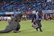 シュートする長谷川博己（右）とボールの行方を見つめるゴジラ。