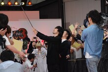 自撮り棒を使いファンとの写真撮影を行う山田孝之。