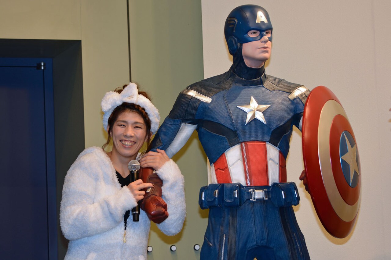 キャプテン・アメリカのフィギュアと腕を組む吉田沙保里。