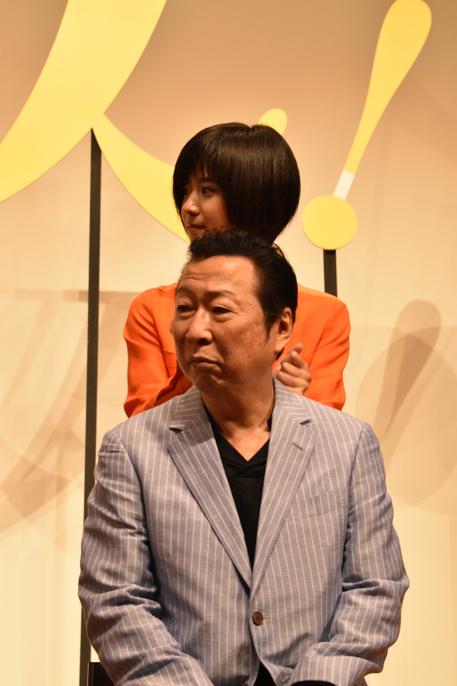 石倉三郎（前）の肩をたたく黒島結菜（後）。