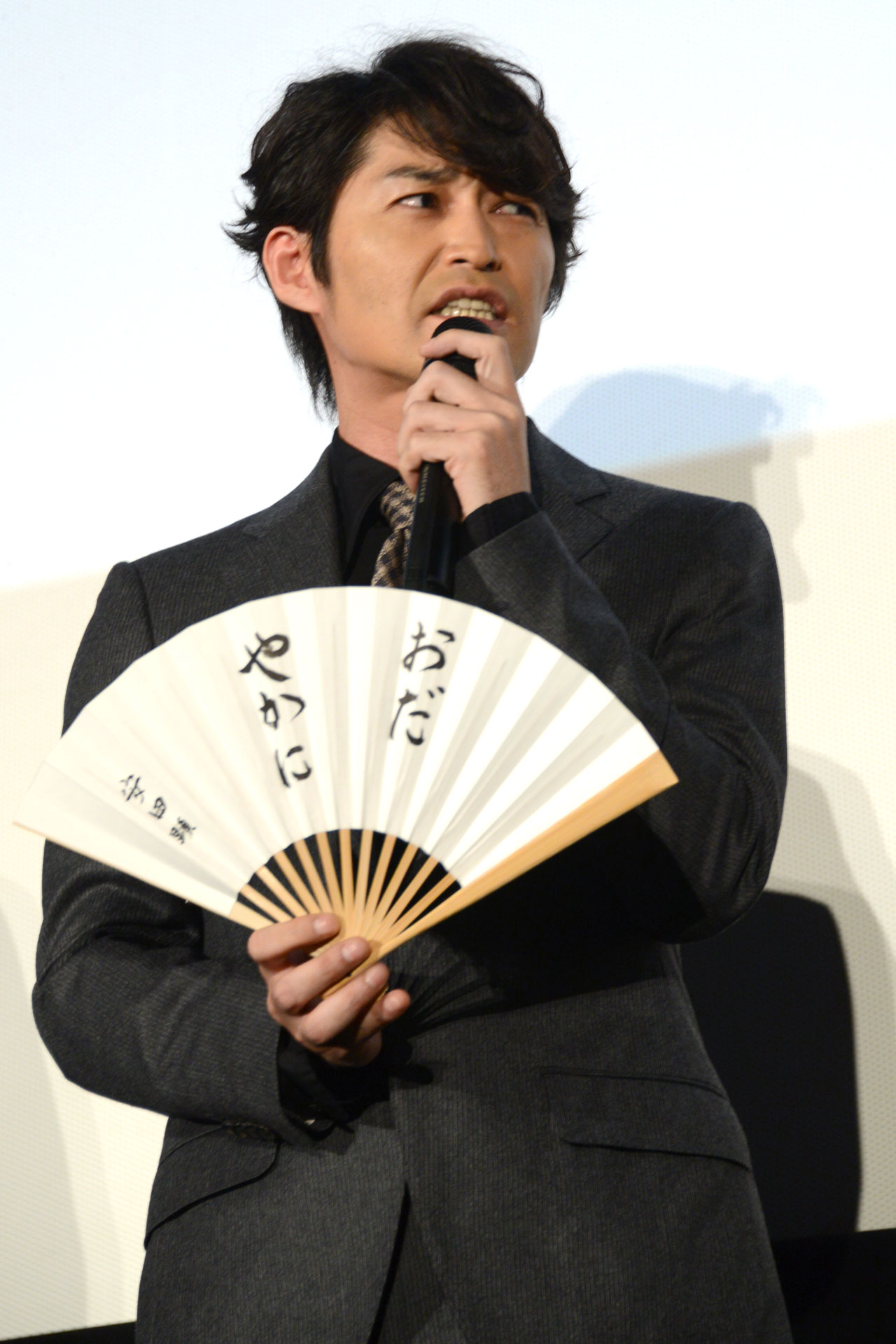 座右の銘を記した扇子を見せながら、自身のせっかちさに言及する安田顕。