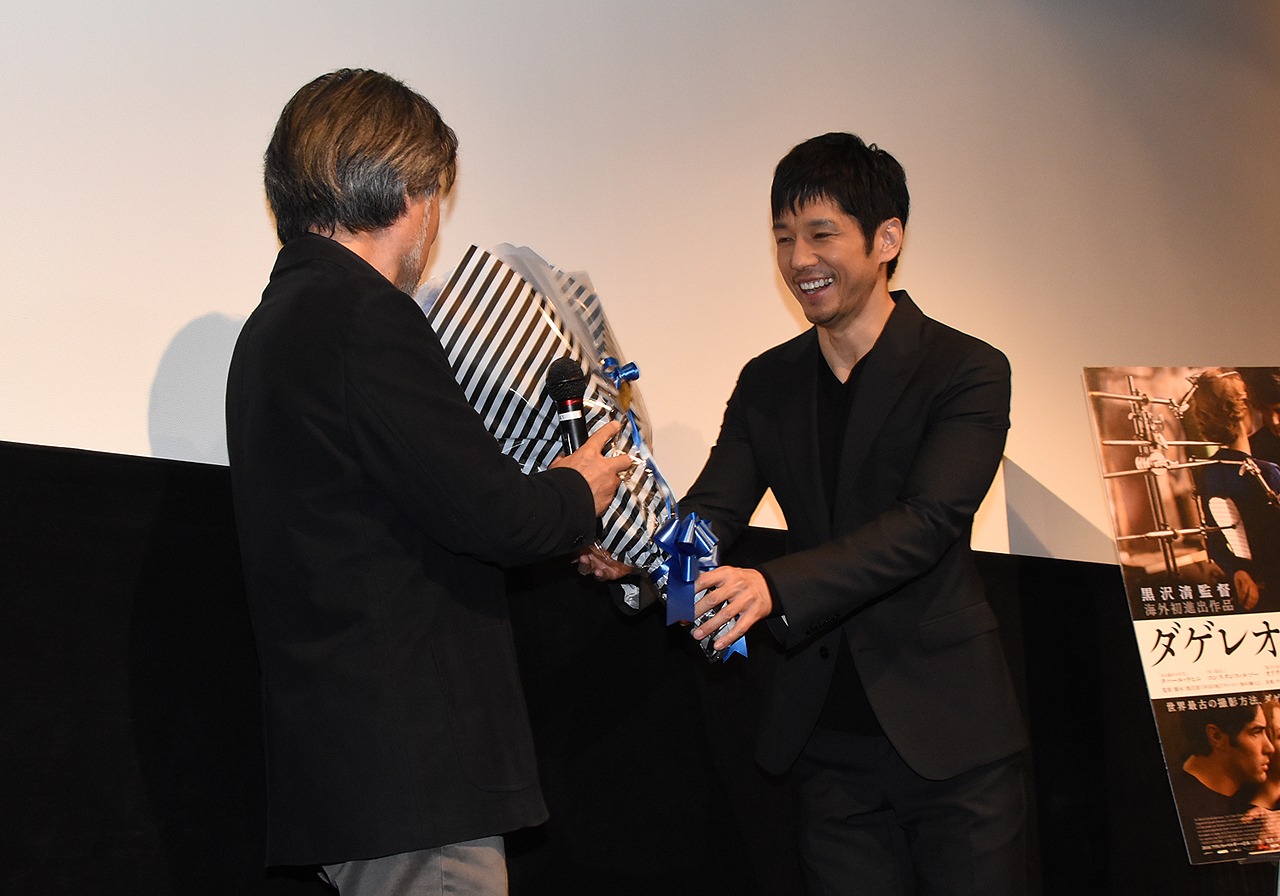 「ダゲレオタイプの女」初日舞台挨拶より、黒沢清（左）に花束を手渡す西島秀俊（右）。