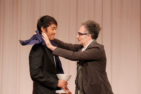 副賞であるスカーフを、デザイナーのミハイル・ギニス（右）にかけられた阿部寛（左）。