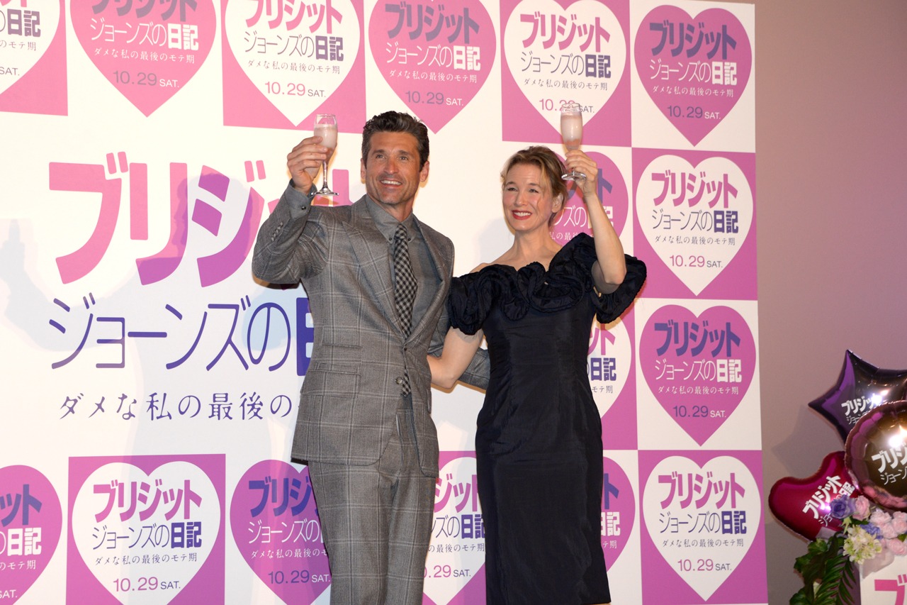 「カンパイ！」の音頭とともにグラスを掲げるレニー・ゼルウィガー（右）とパトリック・デンプシー（左）。