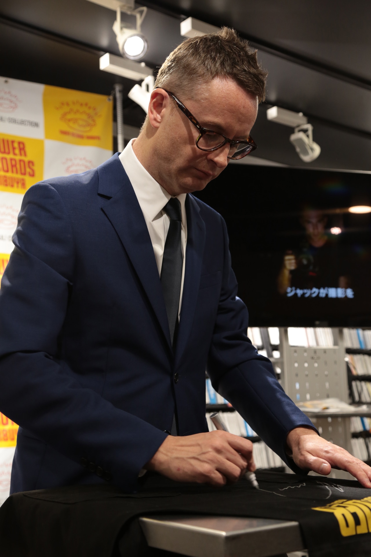 タワーレコード店員のエプロンにサインするニコラス・ウィンディング・レフン。