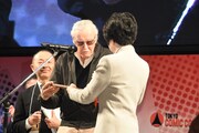 名誉親善大使任命状を授与されるスタン・リー（中央）。