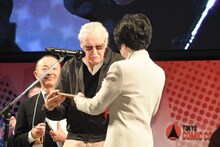 名誉親善大使任命状を授与されるスタン・リー（中央）。