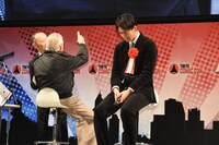 ステージの様子を生中継している背後のモニターを見ながらふざけて「私の背中しか見えないよ！」と言うスタン・リー（左）と、緊張している様子の竹内涼真（右）。