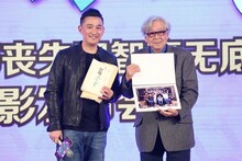 ホアン・レイ（左）のプレゼントを手に持つ山田洋次（右）。