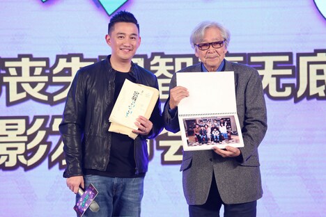 ホアン・レイ（左）のプレゼントを手に持つ山田洋次（右）。