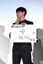 「ぼくは来年、母と旅行をする」と書かれたパネルを見せる東出昌大。