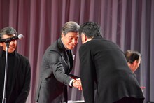 原田眞人（右）と握手する舘ひろし（中央）。