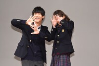 舞台上部に吊られたカーテンが落ち、観客の視線に照れて顔を隠す中川大志（左）と飯豊まりえ（右）。