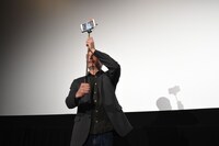 撮った写真を観客に見せようとするマッツ・ミケルセン。