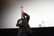 撮った写真を観客に見せようとするマッツ・ミケルセン。