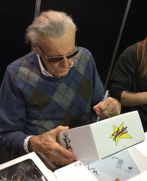 フィギュアの箱にサインをするスタン・リー。
