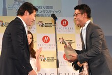 トロフィーを受け取る駿河太郎（右）。