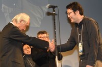 審査員長の内藤誠（左）と握手するグランプリ受賞者の永山正史（右）。