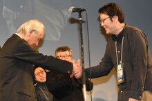 審査員長の内藤誠（左）と握手するグランプリ受賞者の永山正史（右）。