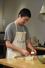 豆腐をカットする新井浩文。