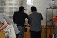 茶碗を洗う松浦祐也（左）と山本浩司（右）。