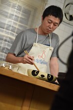 パンダの絵が描かれた“グッチ裕三のフライパンダ”で肉を炒める新井浩文。