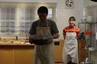 完成したチゲ鍋を運ぶ新井浩文（中央）。