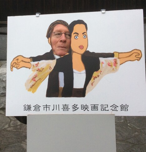 「ケイト・ウィンスレットの顔はどこ？」と確認しながら、「タイタニック」のワンシーンが描かれた顔ハメ看板で遊ぶジャン＝ピエール・ダルデンヌ。リュックのアドバイスによりメガネをかけている。