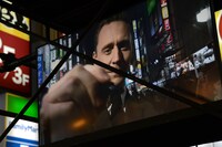 カメラに向かってサインするトム・ヒドルストン。