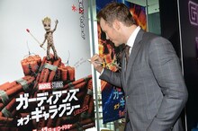 「ガーディアンズ・オブ・ギャラクシー：リミックス」のポスターにサインをするクリス・プラット。