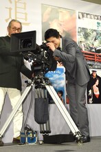 木村大作（左）の指導を受けながらカメラを回す小栗旬（右）。