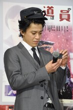 プレゼントの帽子をかぶり、ライターを見つめる小栗旬。