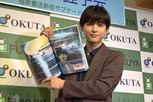 「吉沢亮 PHOTO BOOK『One day off』」より、お気に入りの1枚を掲げる吉沢亮。