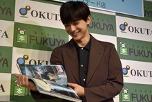 「吉沢亮 PHOTO BOOK『One day off』」より、お気に入りのページを開く吉沢亮。