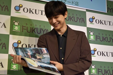 「吉沢亮 PHOTO BOOK『One day off』」より、お気に入りのページを開く吉沢亮。