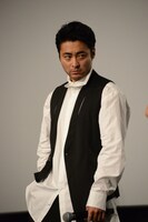 登壇者たちの目を盗み、ポケットから小道具を取り出そうとする山田孝之。