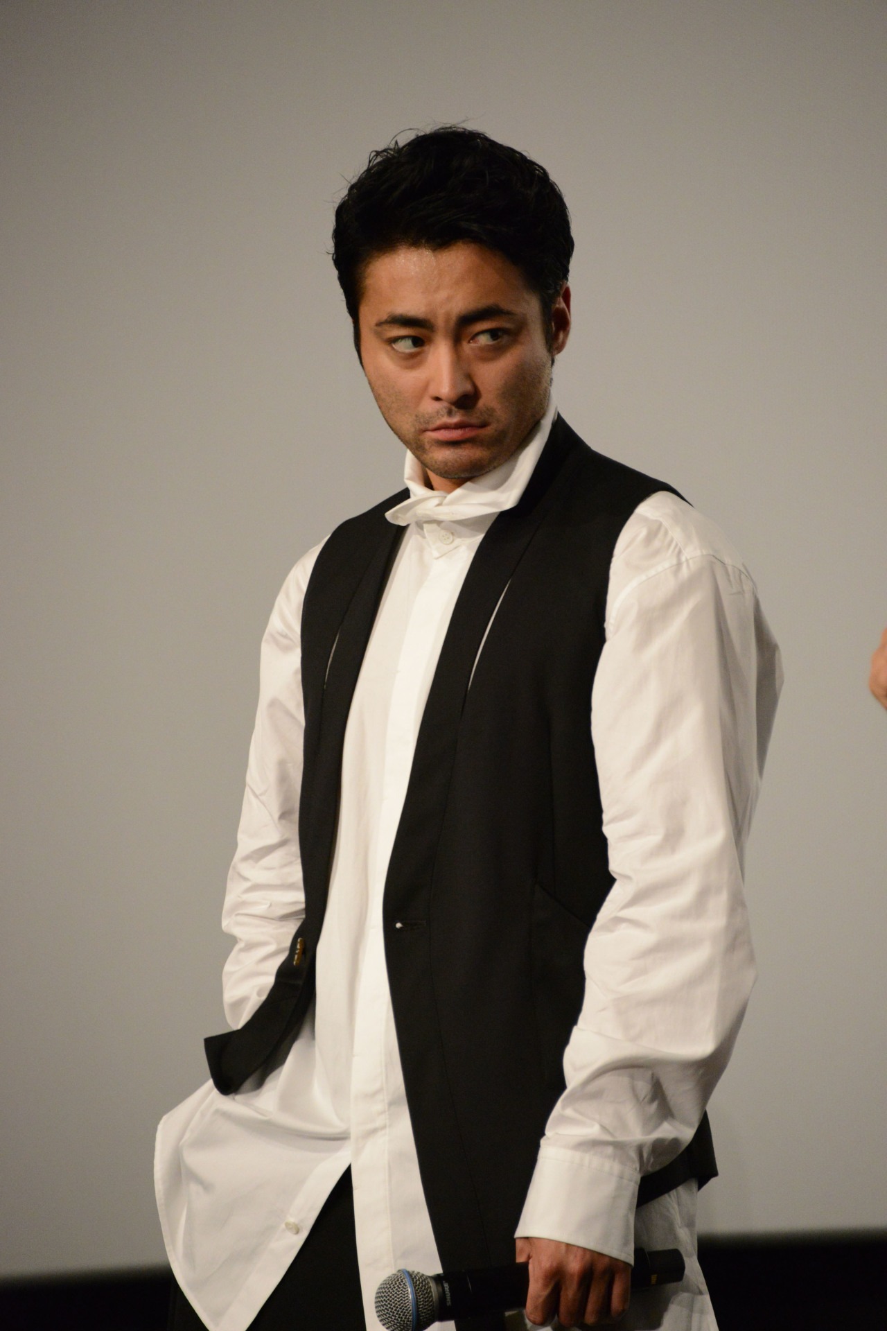 登壇者たちの目を盗み、ポケットから小道具を取り出そうとする山田孝之。