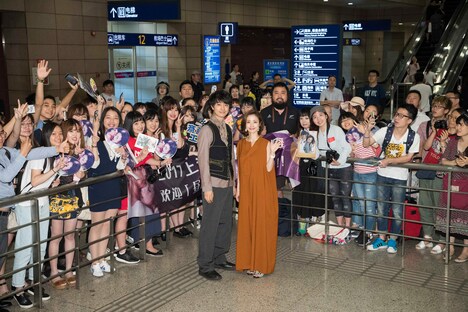 空港でファンと記念撮影をする上戸彩（右）と斎藤工（左）。