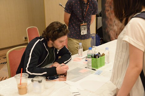 真剣にファンの名前を書くダニエル・ポートマン 。