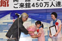 山田洋次（左）が450万人目の来館者に花束を贈呈する様子。