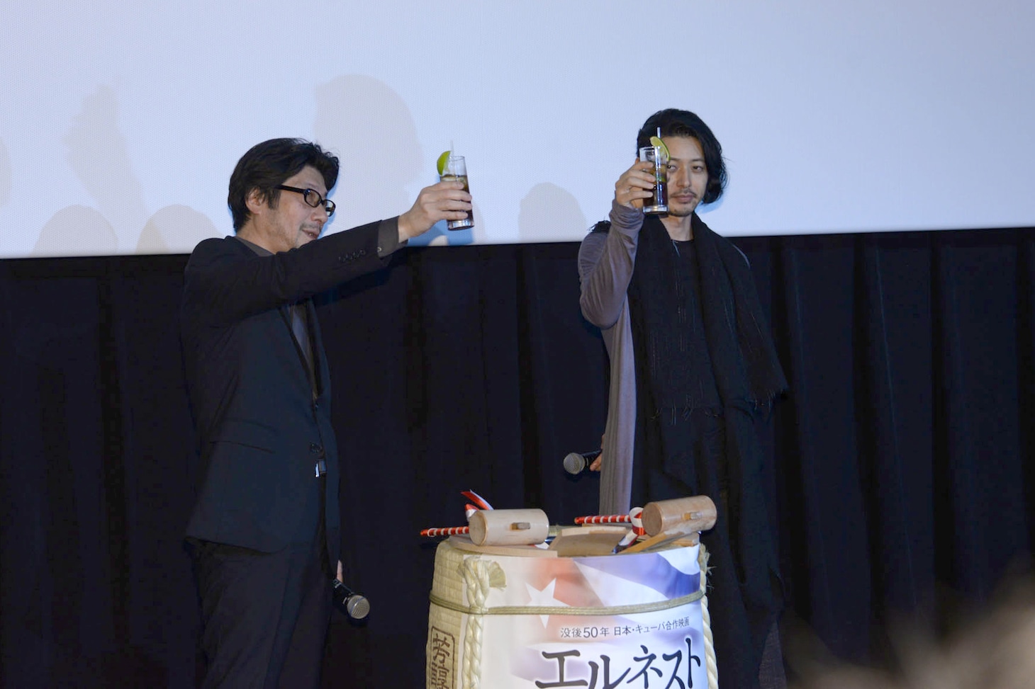 キューバリブレの入ったグラスで乾杯する阪本順治（左）とオダギリジョー（右）。