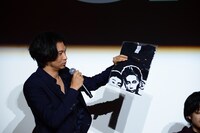 スタッフTシャツを観客に見せる青木崇高。