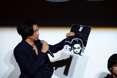 スタッフTシャツを観客に見せる青木崇高。