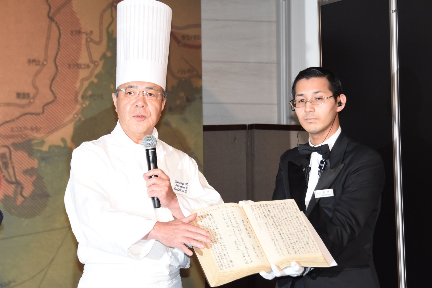 吉川兼吉のレシピを手にする田中健一郎（左）。