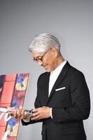 トロフィーをうれしそうな表情で見つめる坂本龍一。