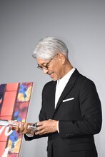 トロフィーをうれしそうな表情で見つめる坂本龍一。