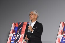 トロフィーをあごに当てる坂本龍一。