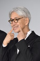 「柔らかい表情でお願いします！」という取材陣のリクエストに応じる坂本龍一。