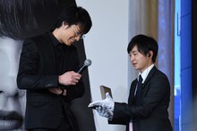 桐谷美玲にブルガリのネックレスを着けることになった鈴木伸之（左）。